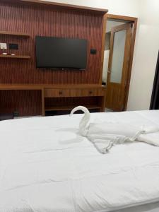 a bedroom with a white bed with a flat screen tv at Mangro villa in Mayyanād