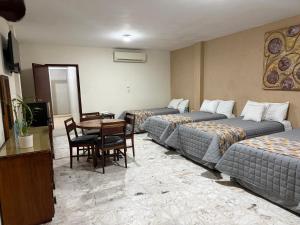 a hotel room with two beds and a table and chairs at Hotel Plaza in Tuxpan de Rodríguez Cano