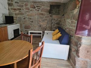 a room with a table and a couch in a stone wall at Lobios House in Bubaces