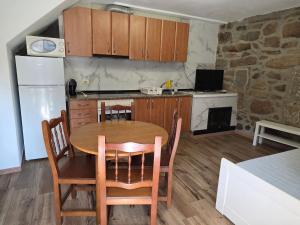 a kitchen with a wooden table and a kitchen with a refrigerator at Lobios House in Bubaces