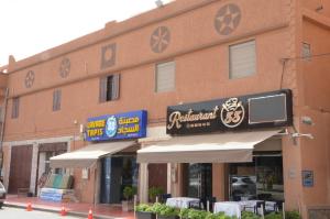 a building with a sign for a restaurant with tables at Residence 33 vèrte in Guelmim