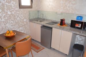 a kitchen with a sink and a table with a bowl of fruit at Residence 33 vèrte in Guelmim