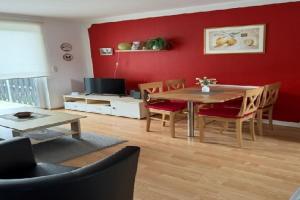 a living room with a table and chairs and a red wall at Gemuetliche Doppelhaushälfte in Lubmin in Lubmin