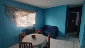 a blue room with a table and a blue couch at Conforto in Maricota