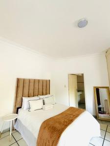 a bedroom with a large white bed with a wooden headboard at Homely Palace in Midrand +21 photos