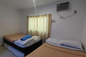 two beds in a small room with a window at Liane's Place Puerto Princesa in Puerto Princesa City