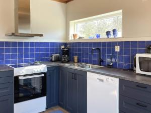 a blue tiled kitchen with a sink and a microwave at 4 person holiday home in KLINTEHAMN-By Traum in Klintehamn +24 photos