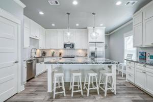 a kitchen with white cabinets and a large island with stools at Hannah Cabana home in Crystal Beach +34 photos