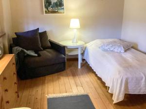 a bedroom with a bed and a chair and a lamp at 4 star holiday home in ELDSBERGA in Eldsberga