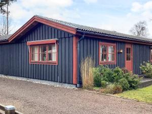 a blue house with red windows on the side of it at 4 star holiday home in ELDSBERGA in Eldsberga