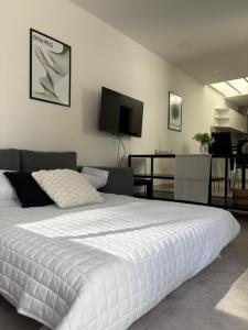 a bedroom with a large white bed and a tv at Patios de City Bell Hotel and Apartments in City Bell +21 photos