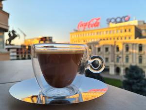 a glass cup of coffee on a plate on a table at MIKA Square in Skopje