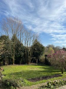 a grassy field with trees and bushes in a park at Charmante maison en pleine campagne in Rollancourt