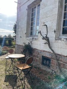 a table and chairs in front of a brick building at Charmante maison en pleine campagne in Rollancourt +1 photo