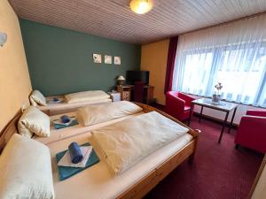 a hotel room with two beds and a red chair at Eiscafé - Pizzeria Antonio in Lichtenau