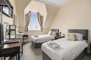 a bedroom with two beds and a desk and a sink at Corran House Guest House in Oban