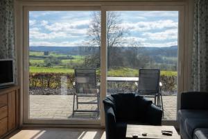 a living room with a sliding glass door with a view at Schwedenhaus Fridhem mit Panoramablick auf dem Hügel in Monschau