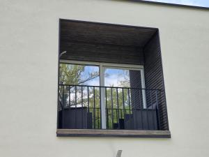 a window of a white building with a balcony at Le Petit L Orée des Bois in Blainville-sur-lʼEau +1 photo