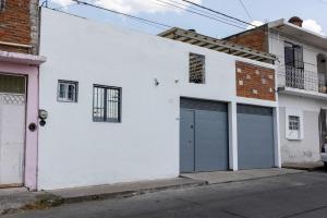a white house with two garage doors on a street at Habitación independencia in Morelia