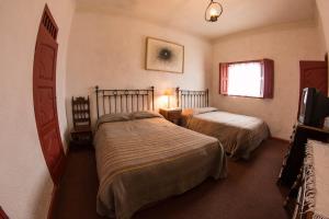 a hotel room with two beds and a window at La Casita de la Basílica in Pátzcuaro