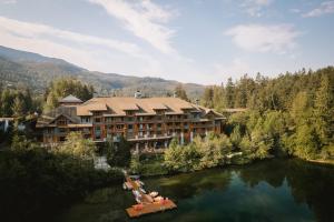 a resort on a river with a boat in the water at Nita Lake Lodge in Whistler