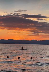 a person on a paddle board in the water at sunset at Le camere del Baldo parcheggio gratuito in centro storico in Peschiera del Garda