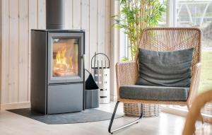 a fireplace in a living room with a chair and a fire at Nice Home In Ringkøbing With Sauna in Ringkøbing
