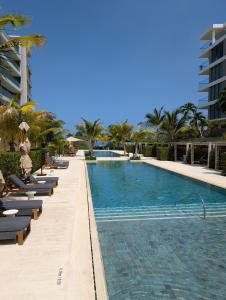 a large swimming pool with chaise lounges and palm trees at Manzanillo Loft Morros EOS in Cartagena de Indias