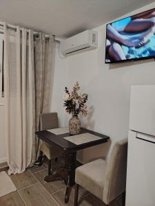 a dining room table with chairs and a tv on the wall at Studio BIANCA in Kotor