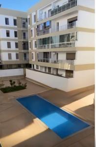 an apartment building with a blue pool in front of it at résidence avec piscine wifi et parking gratuit in Bouskoura