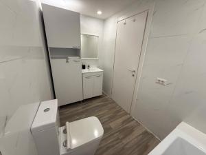 a white bathroom with a toilet and a sink at Olimp Sea View Apartments by Maritimo in Olimp +55 photos