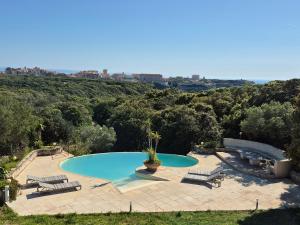 a swimming pool with two chairs and a potted plant at Villa A Macchia, piscine et vue sur Bonifacio in Bonifacio