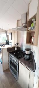 a kitchen with a stove with a pot on it at Twee slaapkamer stacaravan met vissteiger in Hengelo