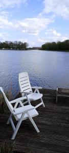 a white chair sitting on a dock near the water at Twee slaapkamer stacaravan met vissteiger in Hengelo