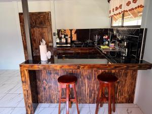 a kitchen with a counter with two bar stools at Cabaña 1 Alajuela, San Carlos, Venecia, Marsella in Pueblo Nuevo