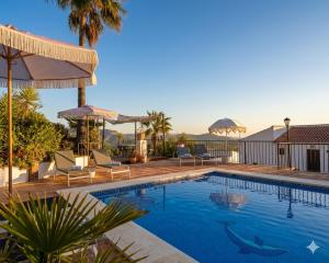 a swimming pool with chairs and umbrellas on a house at Finca Flamenco Holiday Suites Adults Only in Pizarra