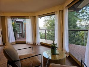 a living room with a table and chairs and large windows at Clouds Serenity in Beechmont