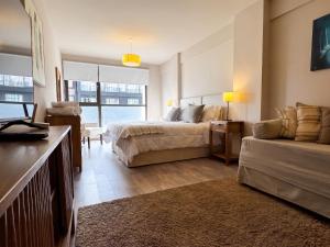 a bedroom with a bed and a couch and a bed and a window at URBANA SUITES & STUDIOS 440 in San Carlos de Bariloche