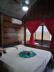 a bedroom with a large bed with red curtains at Cabañas 2 Alajuela, San Carlos, Venecia, Marsella in Pueblo Nuevo