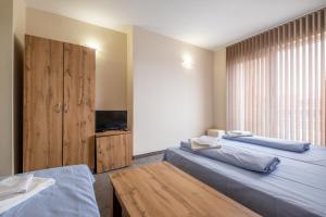 a room with two beds and a table and a television at Julia rooms in Sofia +8 photos