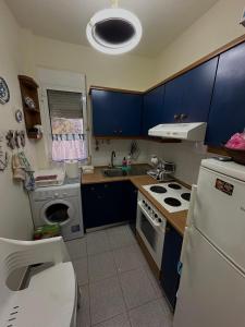 a kitchen with blue cabinets and a white refrigerator at Paradise Coast House in Orfánion