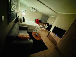 a living room with a bed and a couch at Hei Stays Bachelor Apartment in Bronkhorstspruit