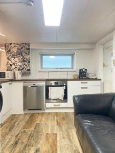 a kitchen with a black couch in a room at Skovhus 2-room Basement Apartment in Aarhus