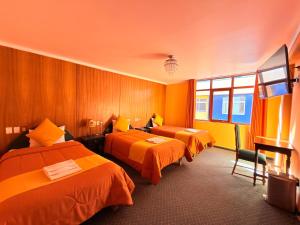 a hotel room with two beds with orange sheets at Hostel Sillustani Inn Puno - Con Cochera in Puno