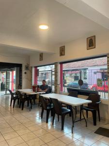 a restaurant with tables and chairs and a person sitting at a table at Yek Hostels in Santa Ana