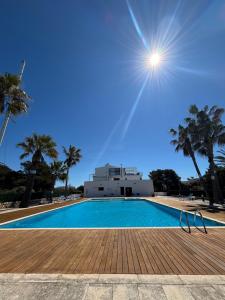 a swimming pool with palm trees and a building at Apartamentos QEli in Son Carrio
