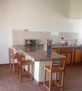 a kitchen with a counter with three chairs and a counter top at Casa verde in Vichayito