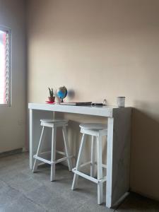 a white desk with two stools in a room at Yek Hostels in Santa Ana