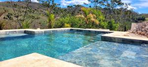 a swimming pool with blue water in a backyard at Pura Vista Lodge in Sámara +25 photos