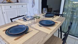 a wooden table with plates and wine glasses on it at L'Échappée Bleue Sea view studio in Moule in Le Moule
